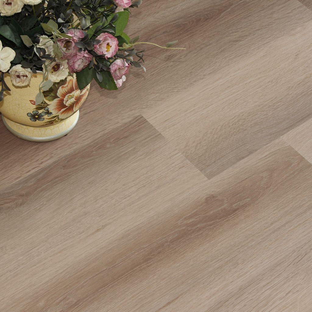 Acogedor dormitorio color beige con tocador, espejo redondo, cama, silla y alfombra suave sobre suelo de madera.