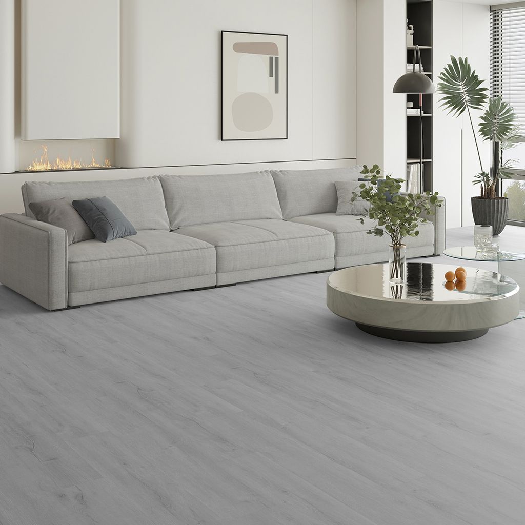 Sala de estar moderna y minimalista con un sofá seccional gris, una mesa de centro redonda y suelo de madera clara.