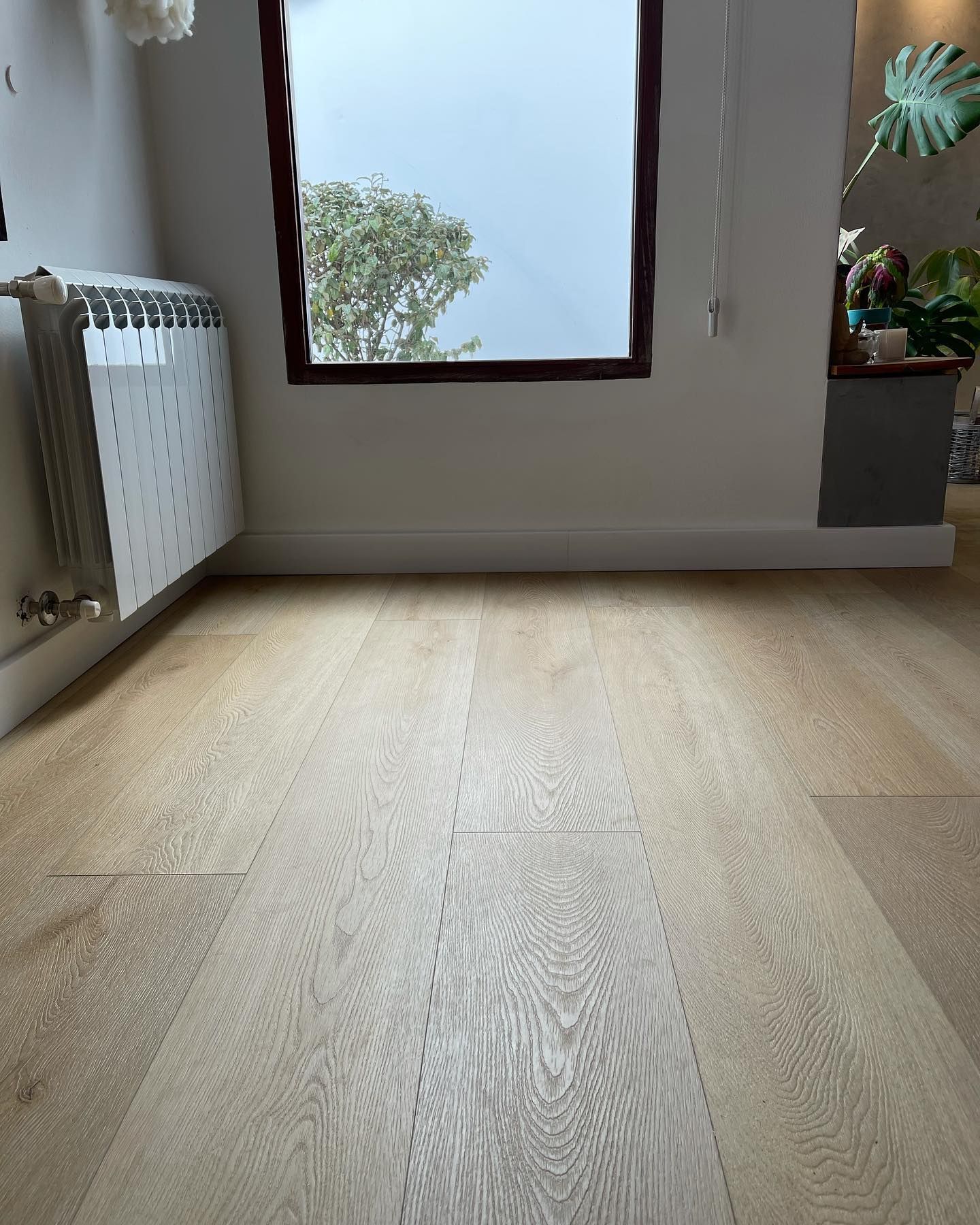 Vestíbulo luminoso y moderno con suelos de madera clara, grandes ventanales y asientos minimalistas