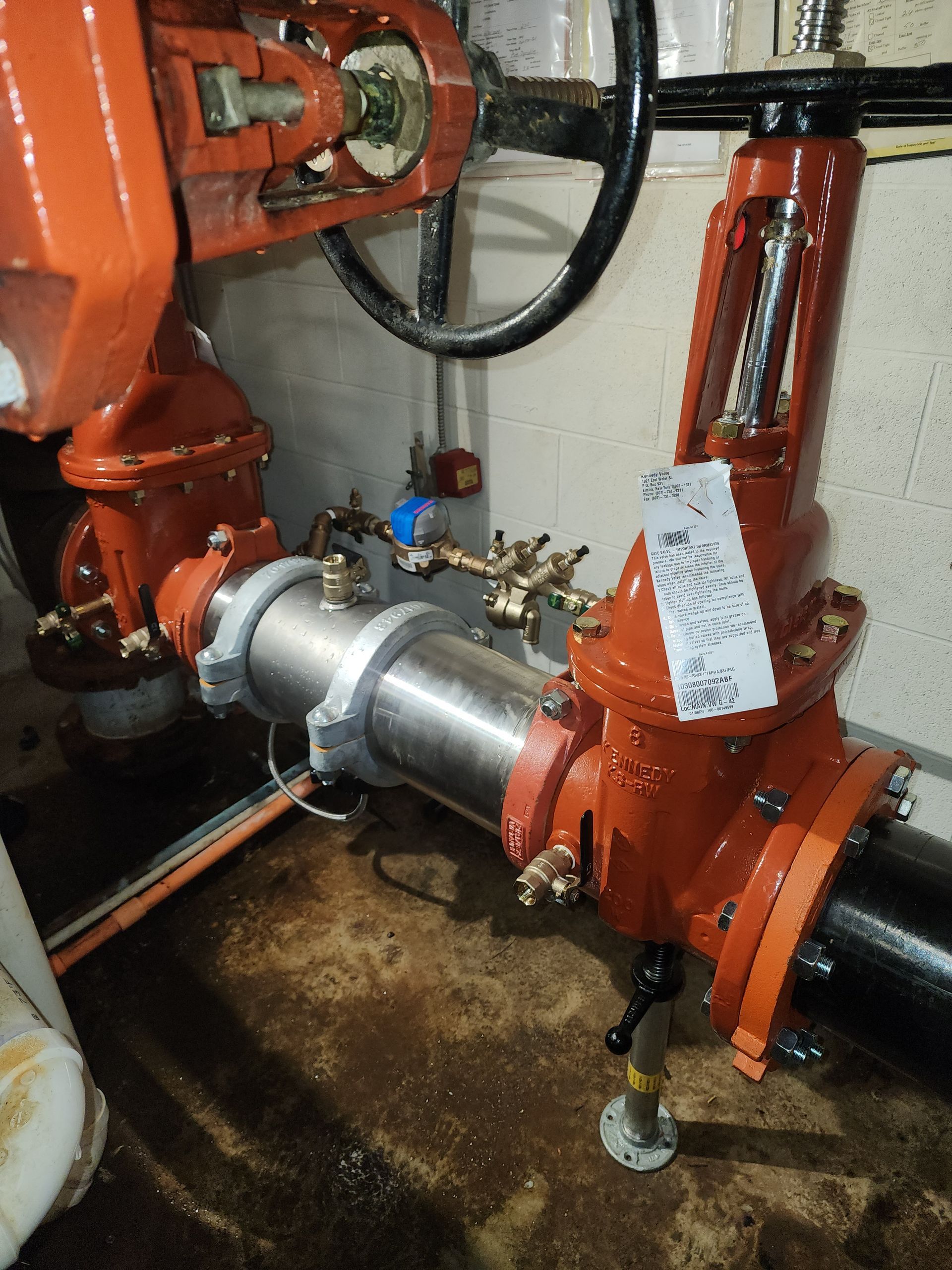 a valve with a tag on it is sitting next to a pipe .