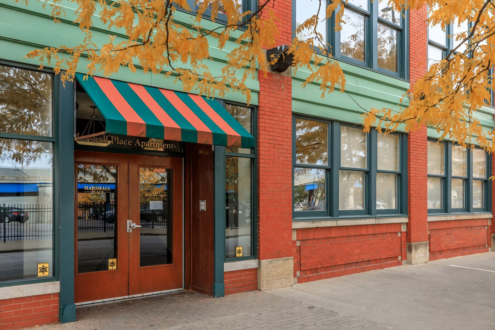 A brick building with a green and orange awning over the door
