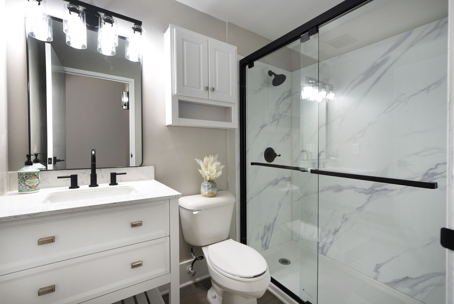 A bathroom with a toilet , sink , mirror and shower.