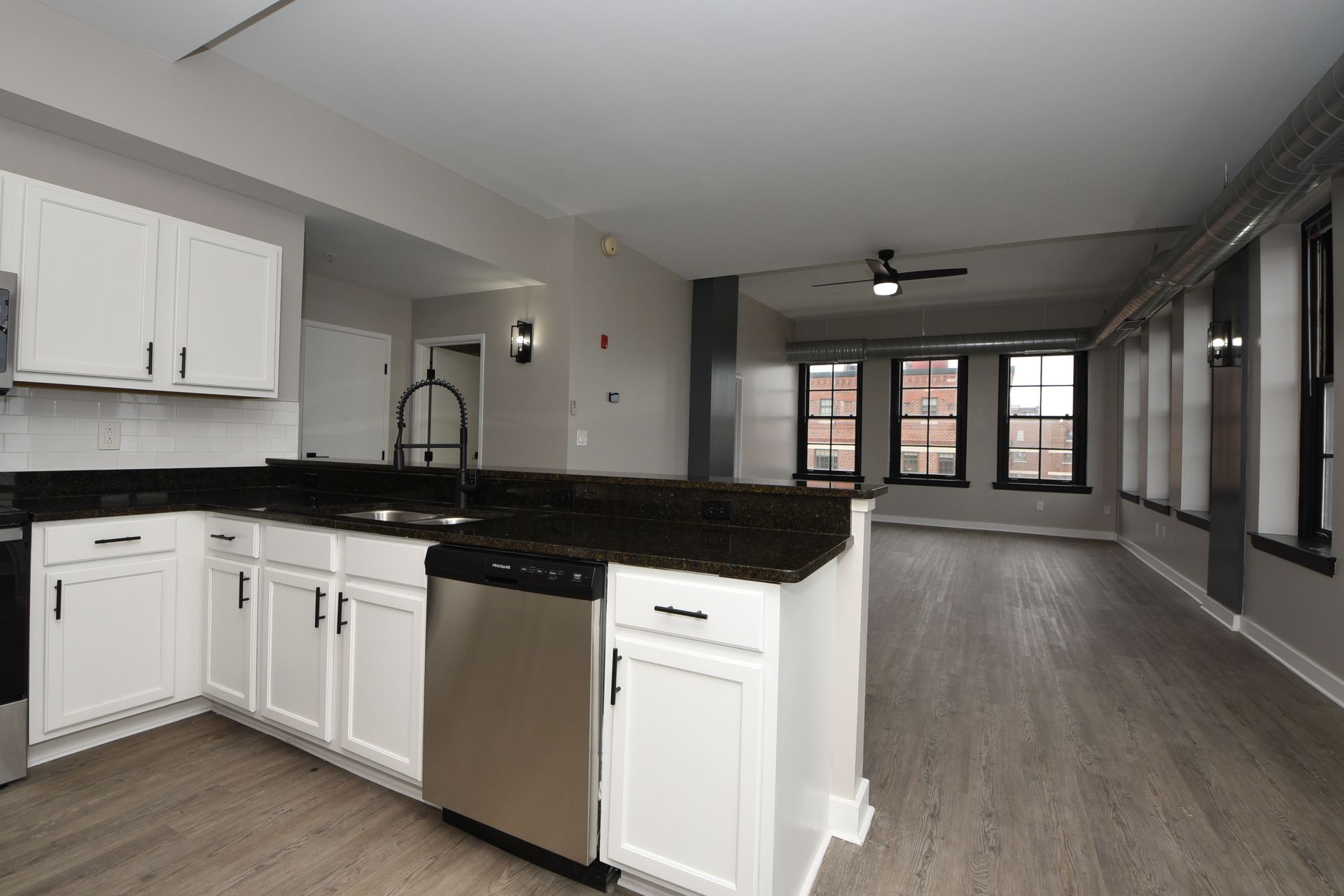 An empty kitchen with white cabinets and stainless steel appliances