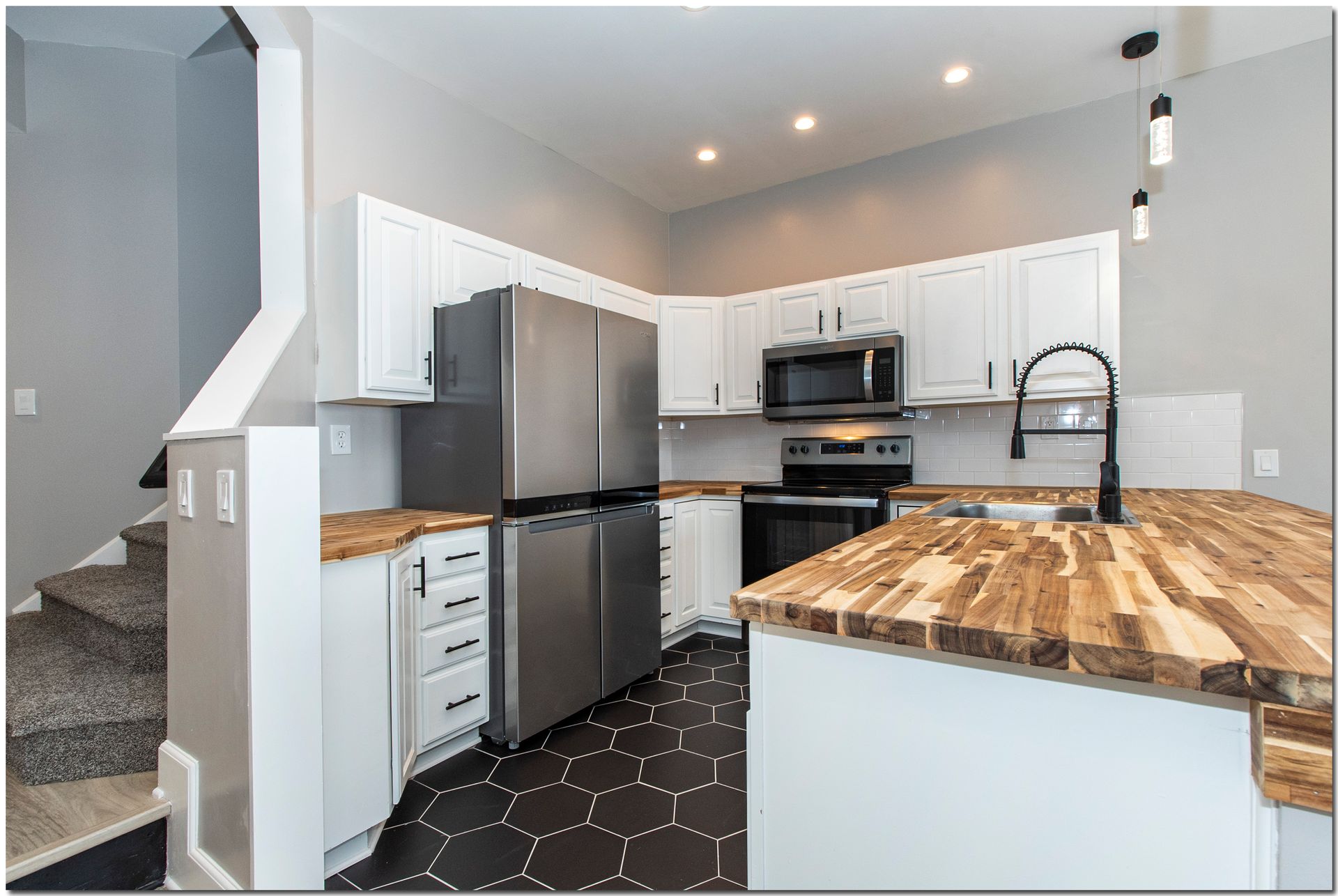 A kitchen with stainless steel appliances and wooden counter tops.
