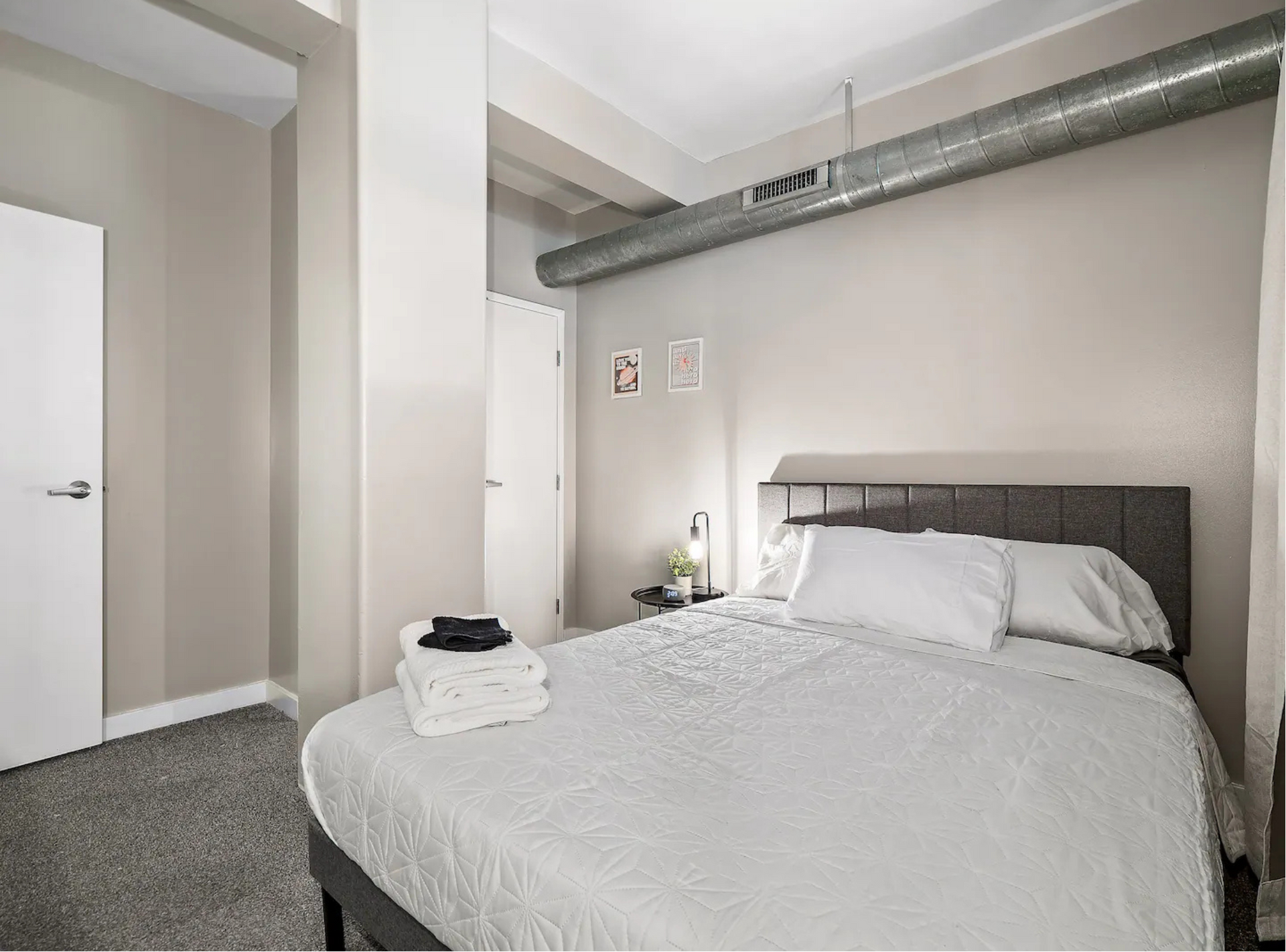 A bedroom with a king size bed and a gray headboard.