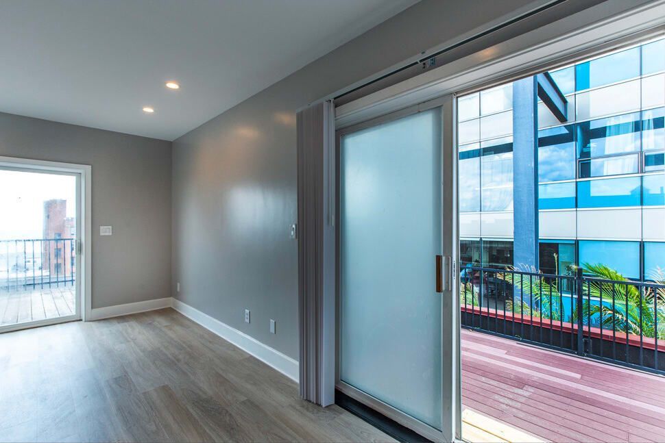 An empty room with a sliding glass door and a balcony.