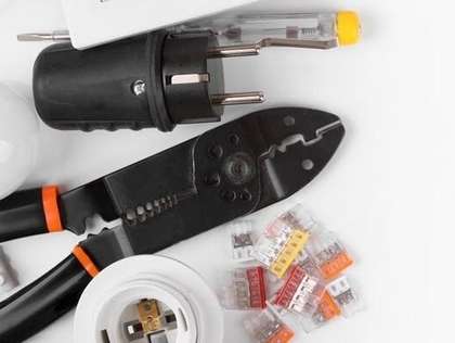 Electrical tools: plug, pliers, wire connectors, screwdriver, and bulb socket on a white surface.