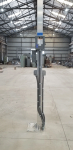A tall metal electrical pole with connected cables, inside an industrial building.