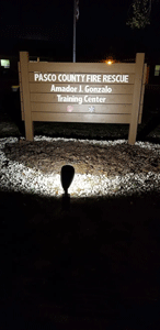 Pasco County Fire Rescue sign at night, illuminated by a spotlight.