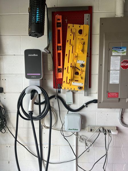 EV charger, electrical panel, and tools mounted on a garage wall.