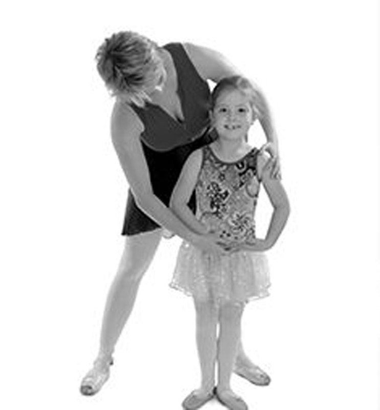 A woman is standing next to a little girl in a tutu.