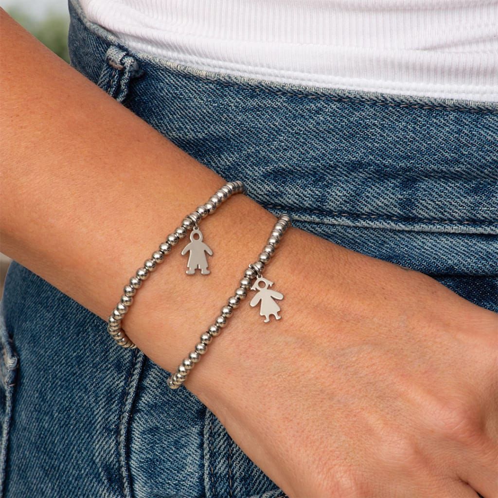 Dos pulseras de cuentas con charms en forma de niño en la muñeca, fondo denim.