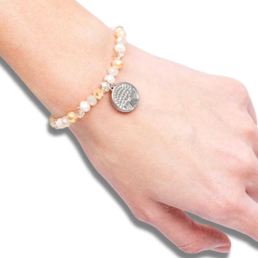 Una mano que lleva una pulsera de cuentas con un dije de plata.