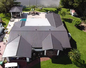 An aerial view of a large house with a brown roof and a pool.