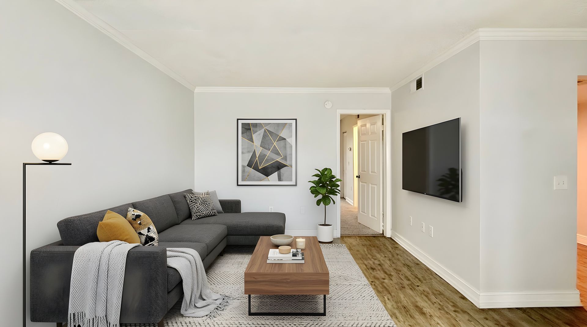 Staged living room with wood floors, sofa and TV