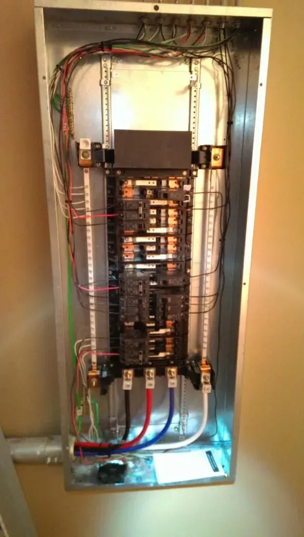Electrical panel with wires and circuit breakers.