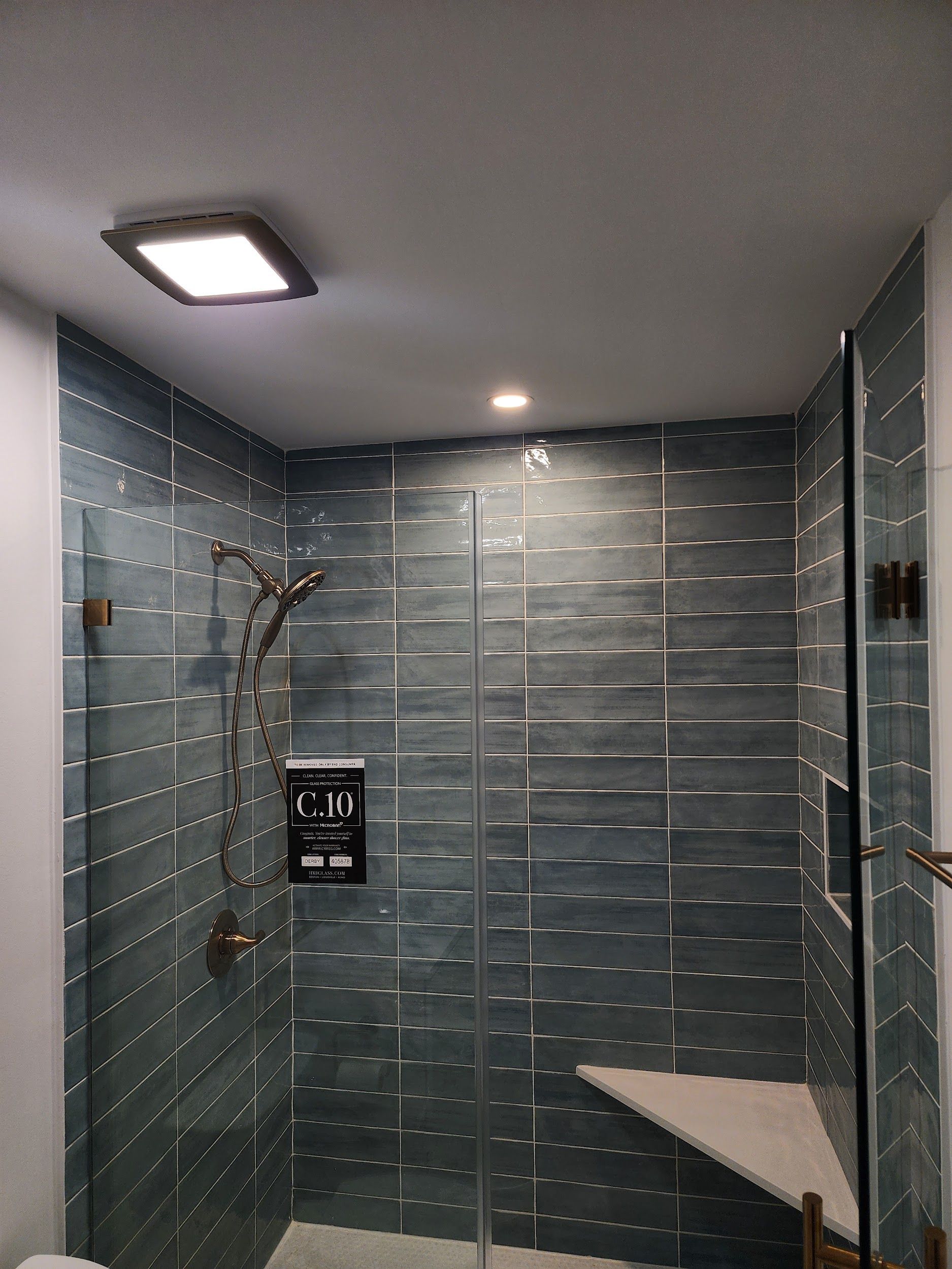 Shower with teal tile walls, glass door, and recessed lighting.
