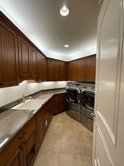 Laundry room with brown cabinets, granite countertops, and stainless steel washer/dryer.