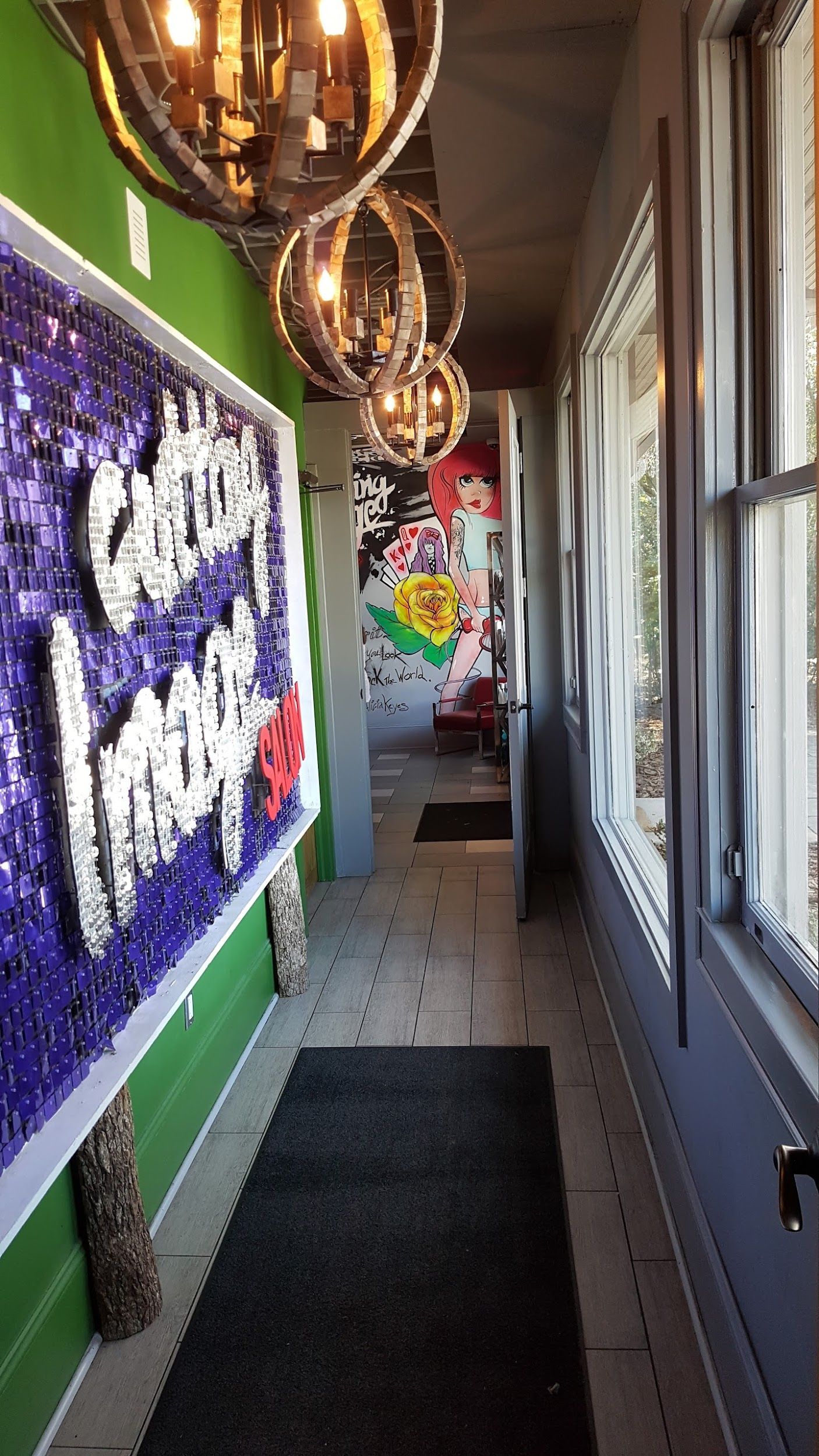 Narrow hallway with gray floor, colorful murals, and globe pendant lights. Windows on right.