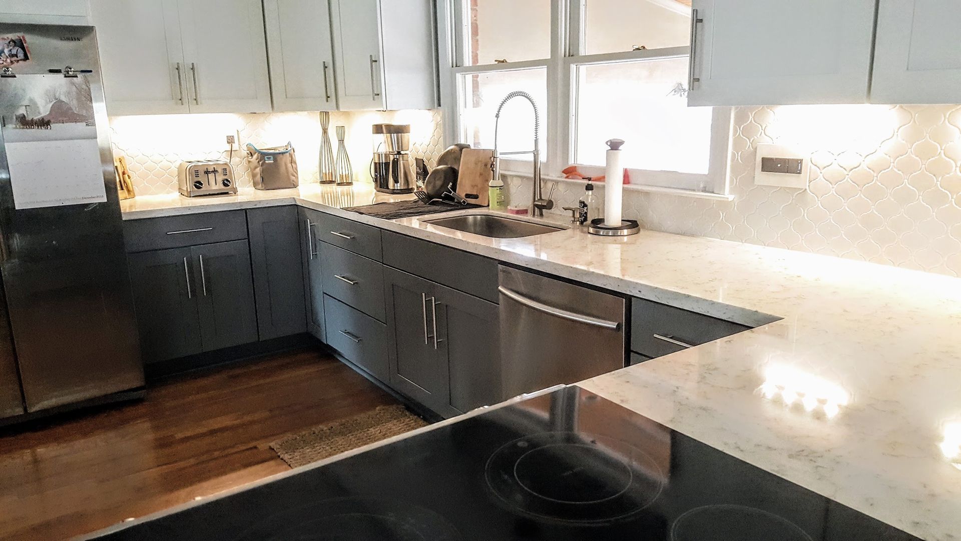 Modern kitchen with gray cabinets, white countertops, and stainless steel appliances.