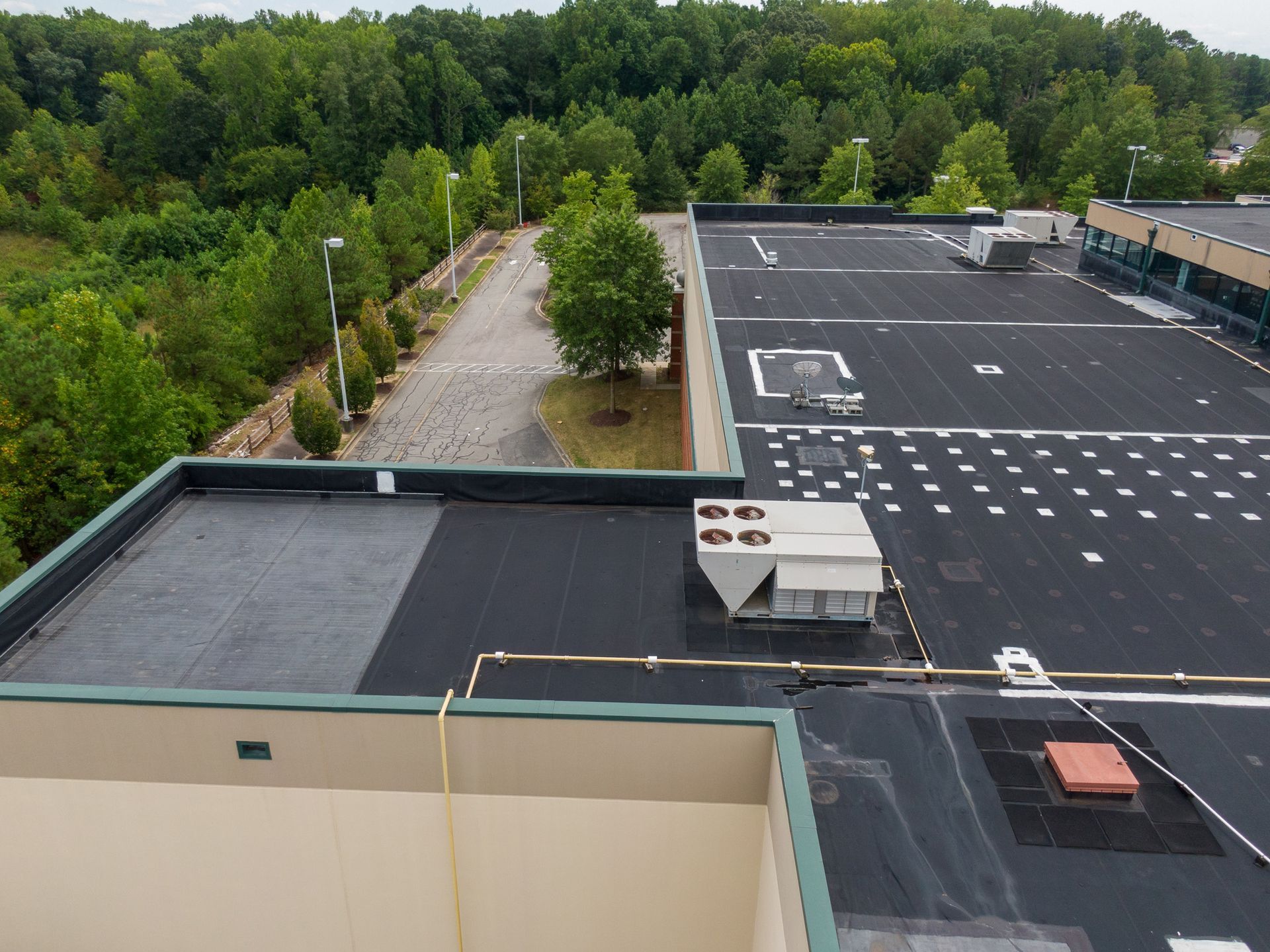 An aerial view of the roof of a building with trees in the background