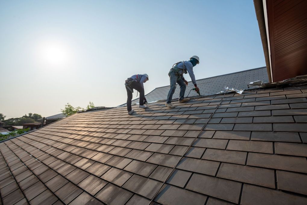 Two men are working on the roof of a house.