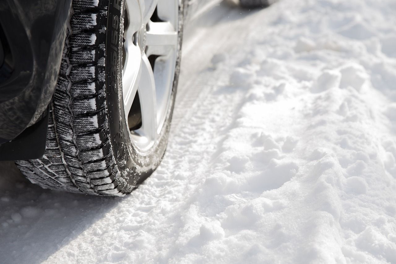 Car tire with winter tread on snow-covered ground, close-up view