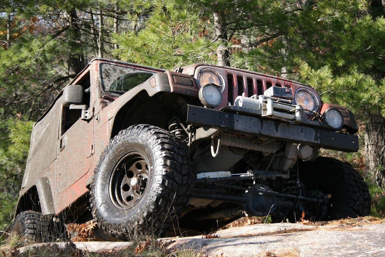 Black off-road Jeep climbing a rocky trail in a wooded area