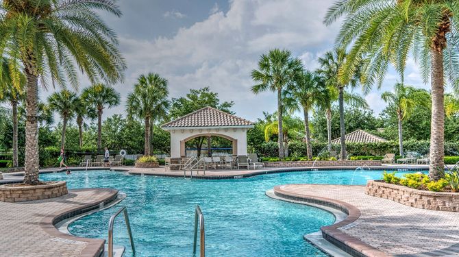 Tropical resort pool with palm trees, blue water, and a gazebo under a bright sky
