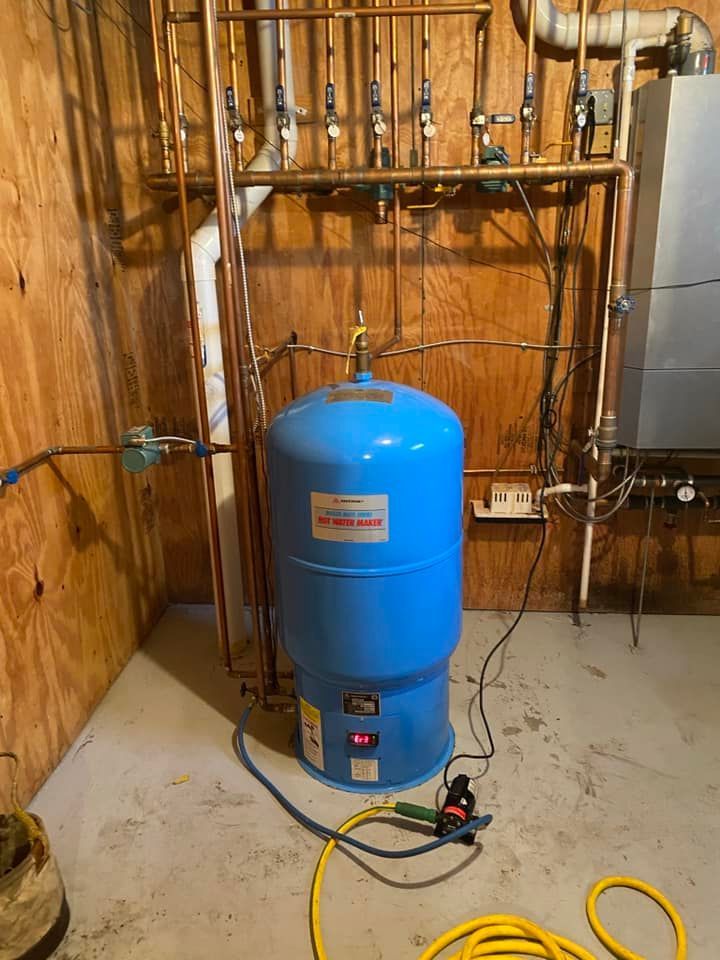 A blue water tank is sitting in a basement next to a boiler.
