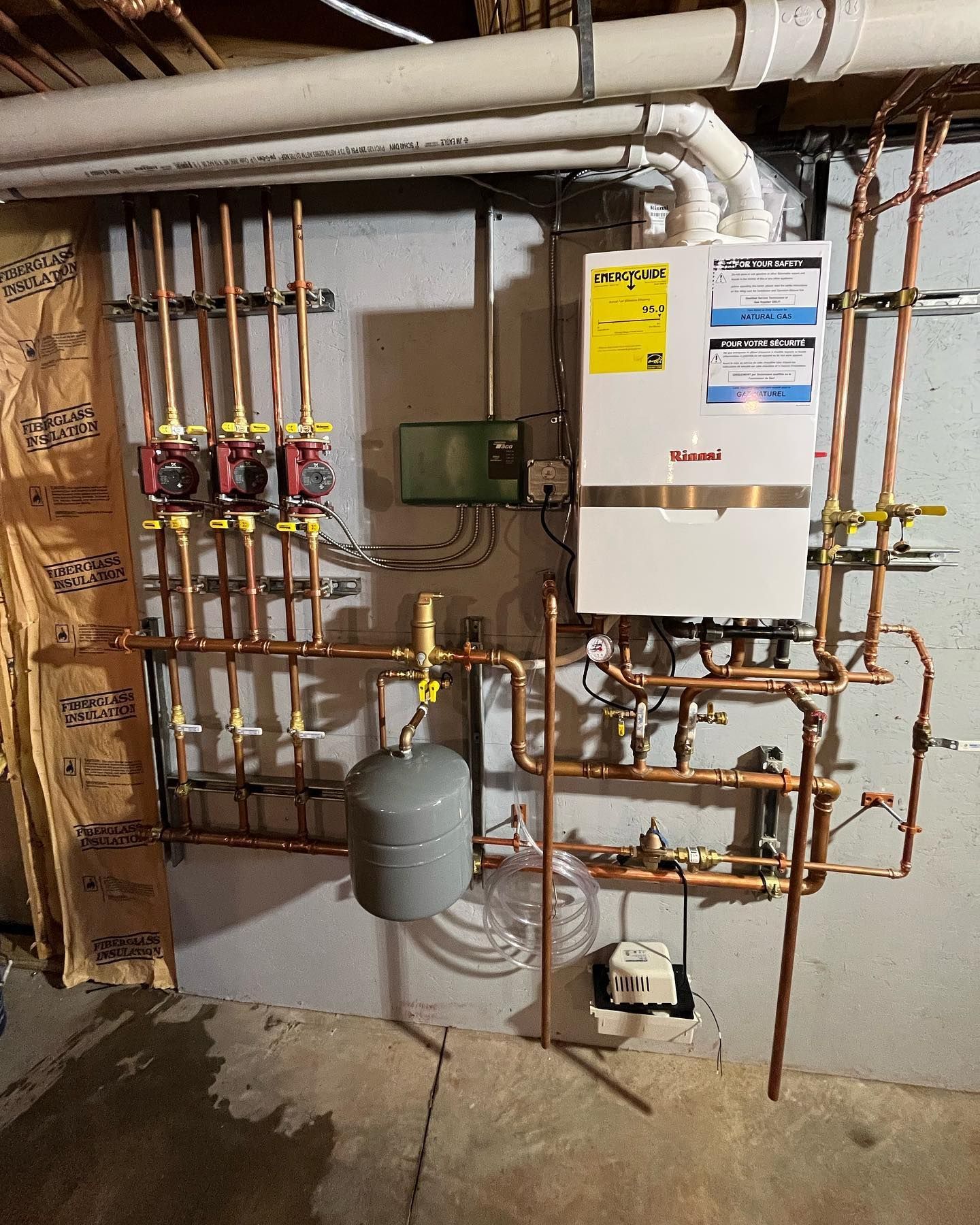 A boiler is installed in a basement with copper pipes.