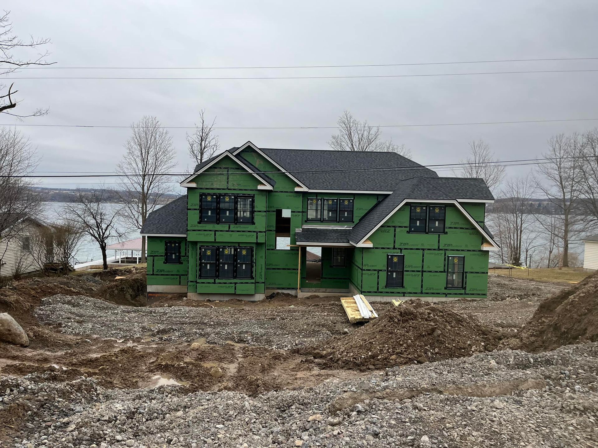 A house is being built on a rocky hillside next to a body of water.