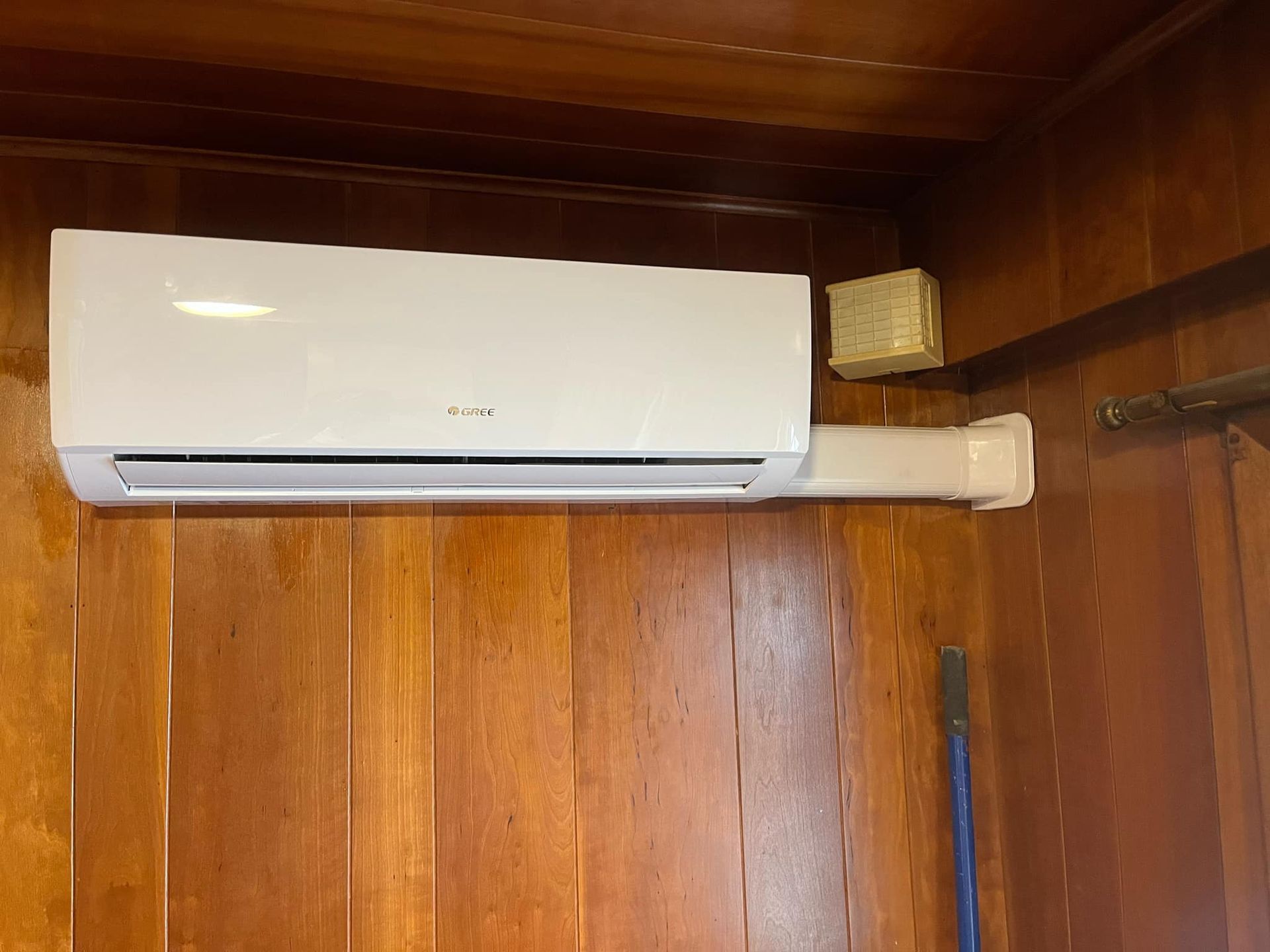 A white air conditioner is hanging on a wooden wall.