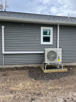 A house with a window and an air conditioner on the side of it.