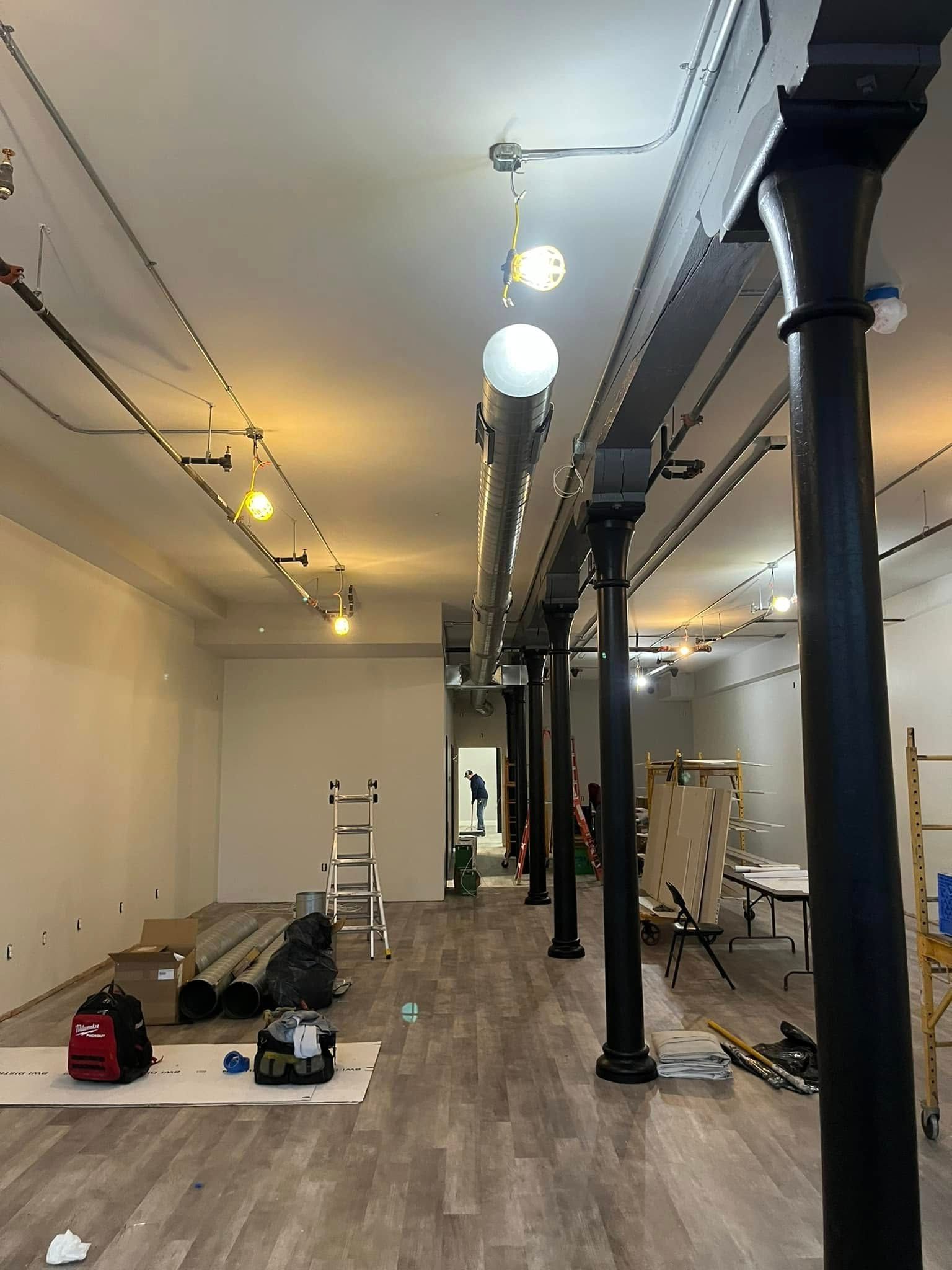 A large empty room with wooden floors and columns.