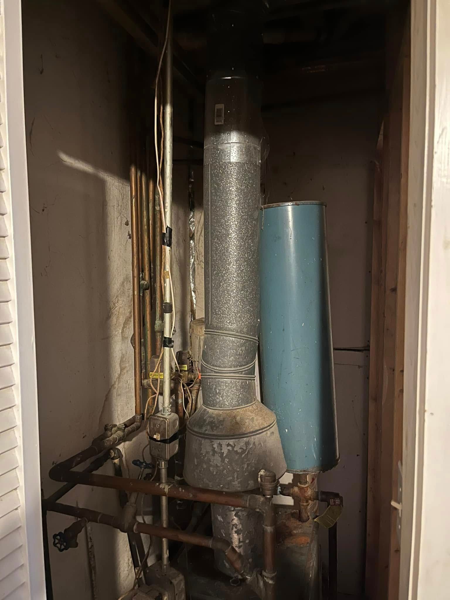 A water heater is sitting in a closet next to a window.