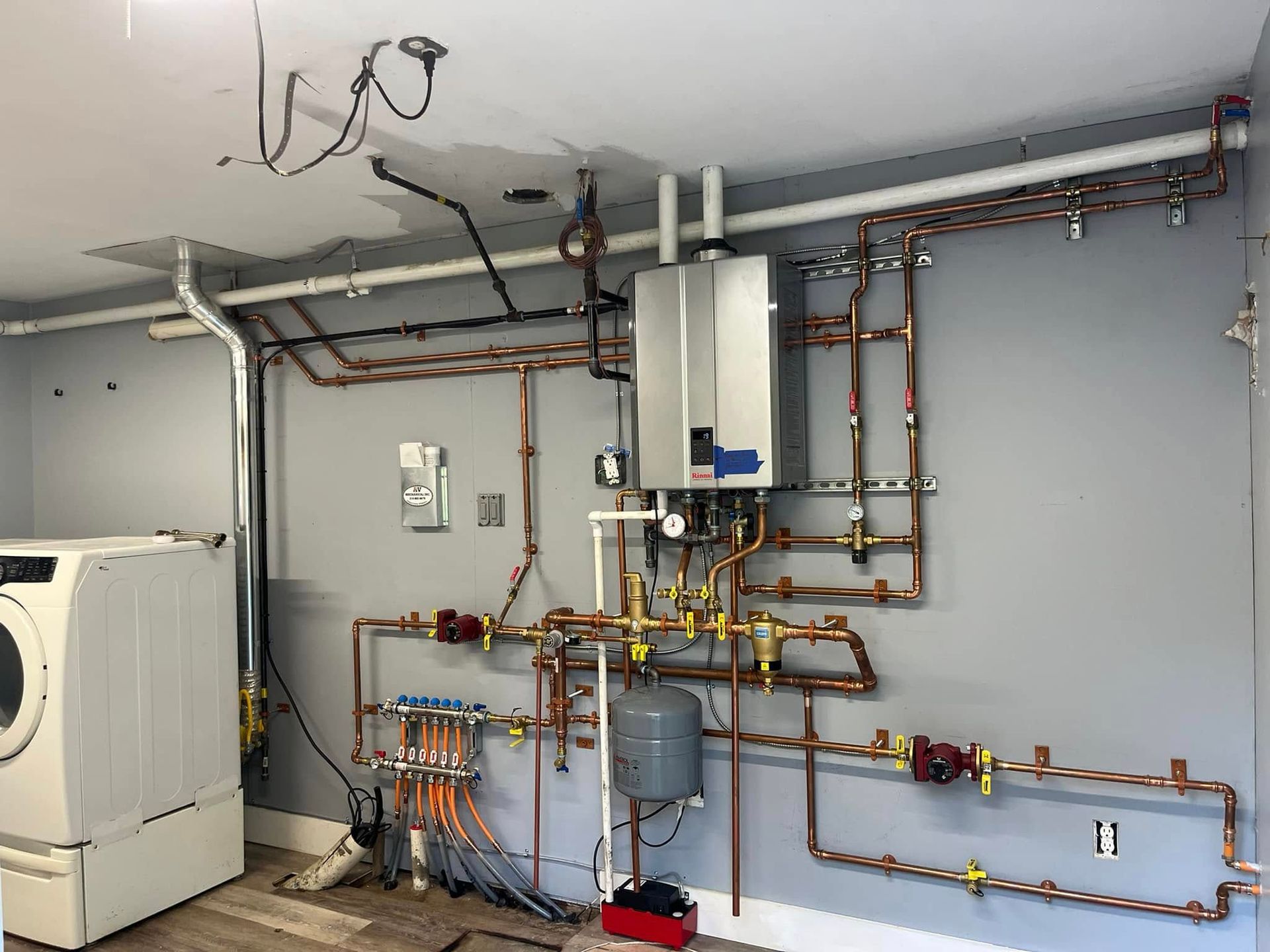 A laundry room with a washer and dryer and a lot of pipes.