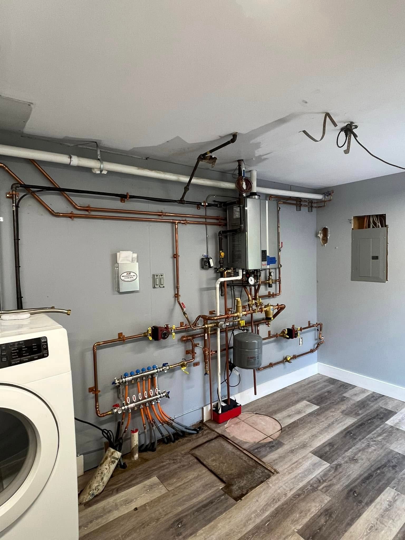 A laundry room with a washer and dryer and a lot of pipes.