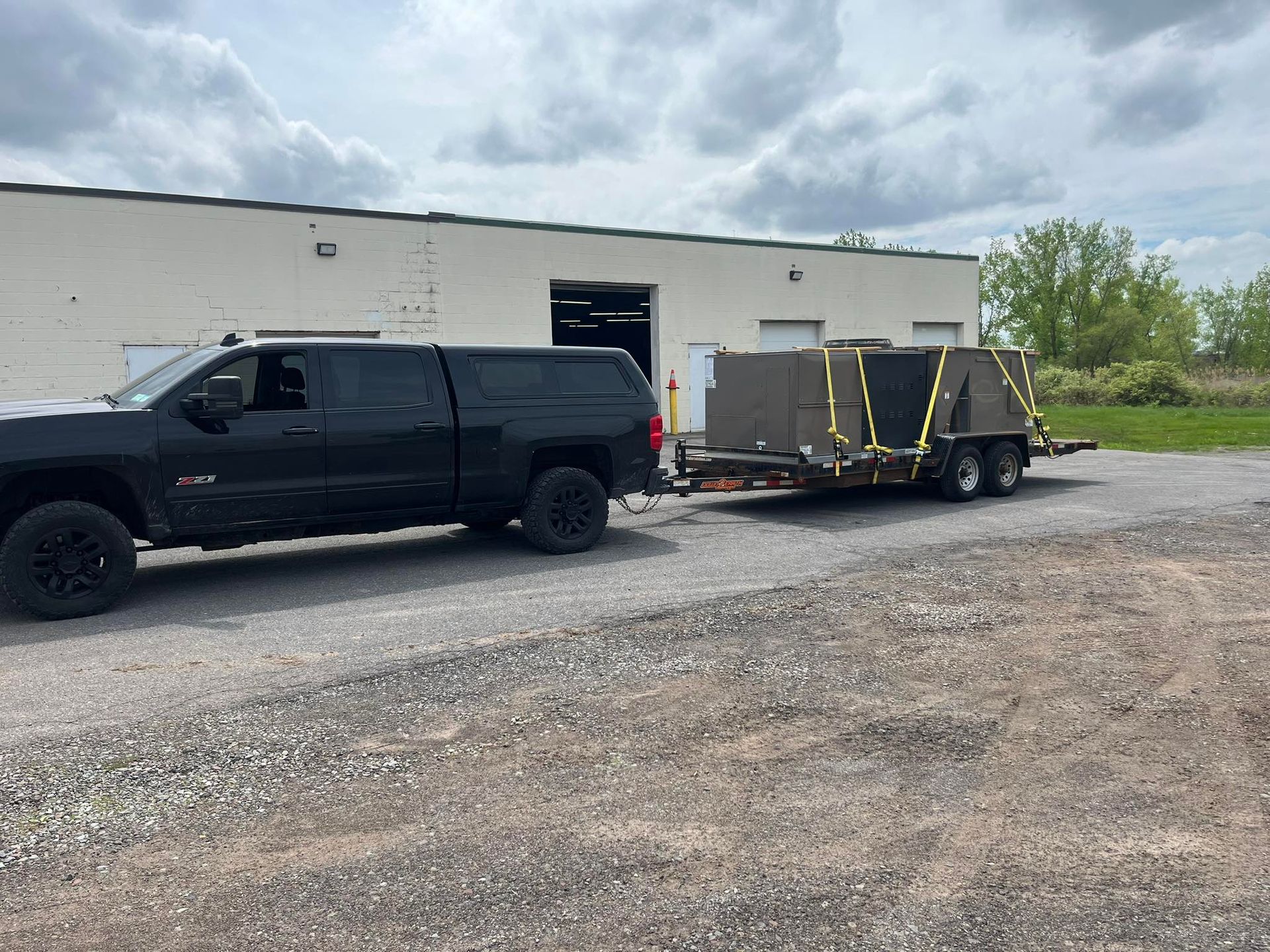 A black truck is towing a trailer in a parking lot.