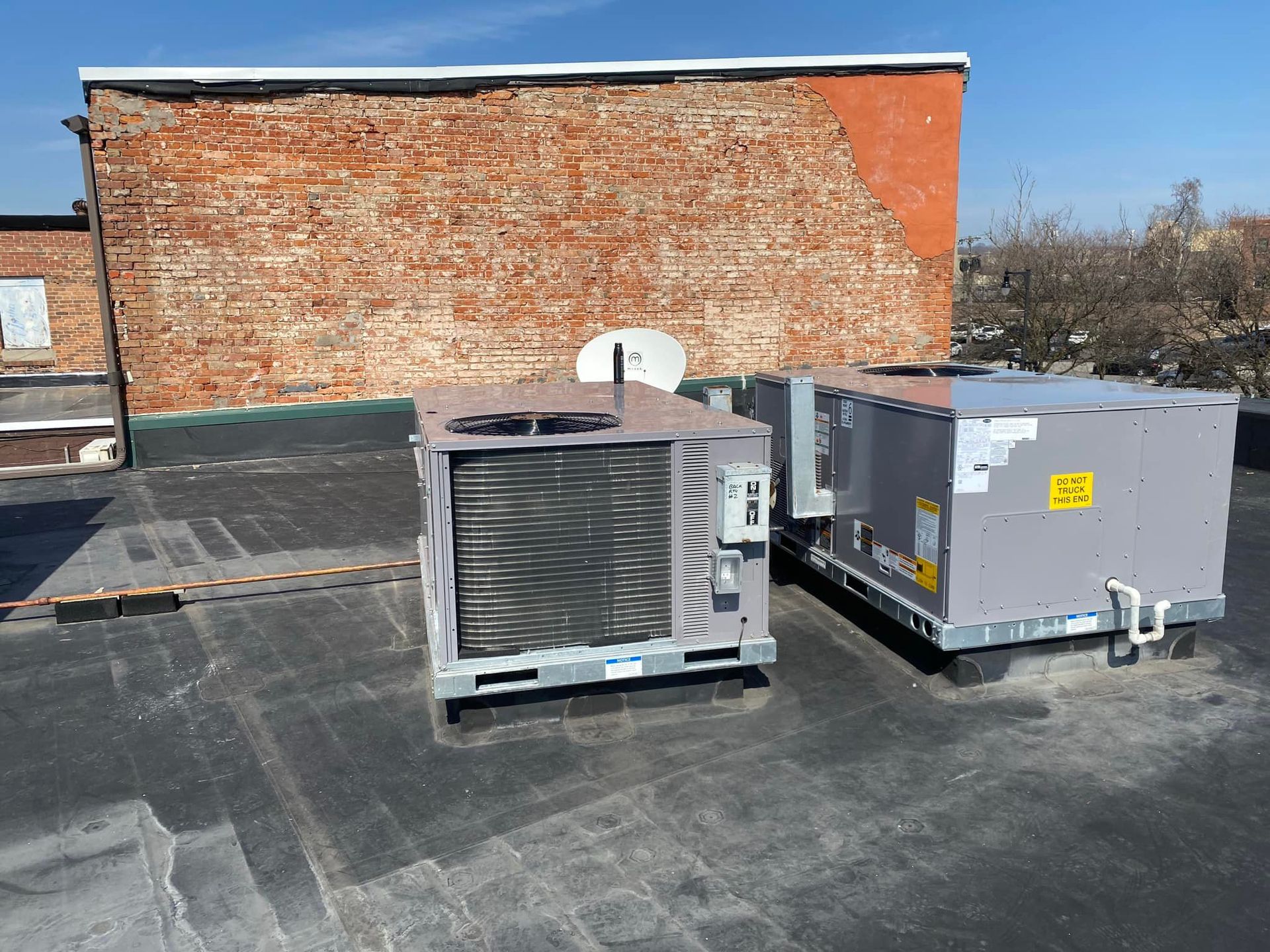 Two air conditioners are sitting on the roof of a building.