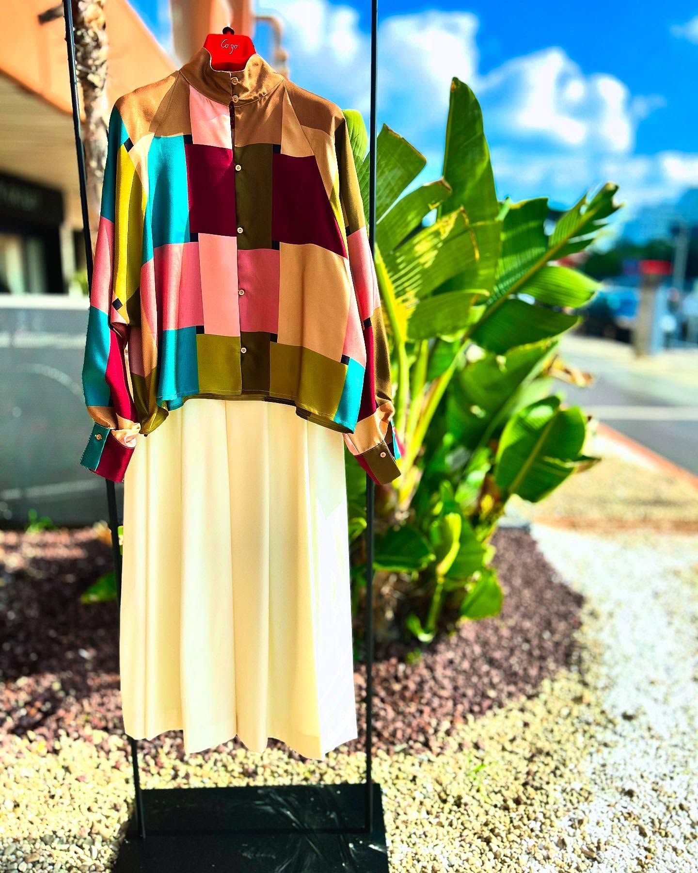 Una giacca e una gonna colorate sono appese su un attaccapanni.