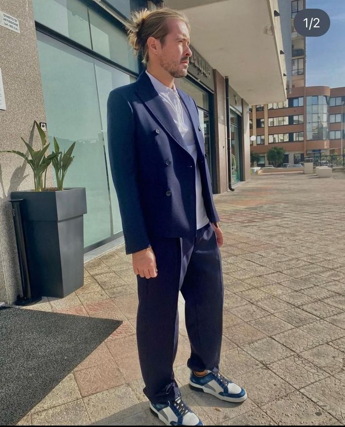 A man in a suit and tie is standing in front of a building