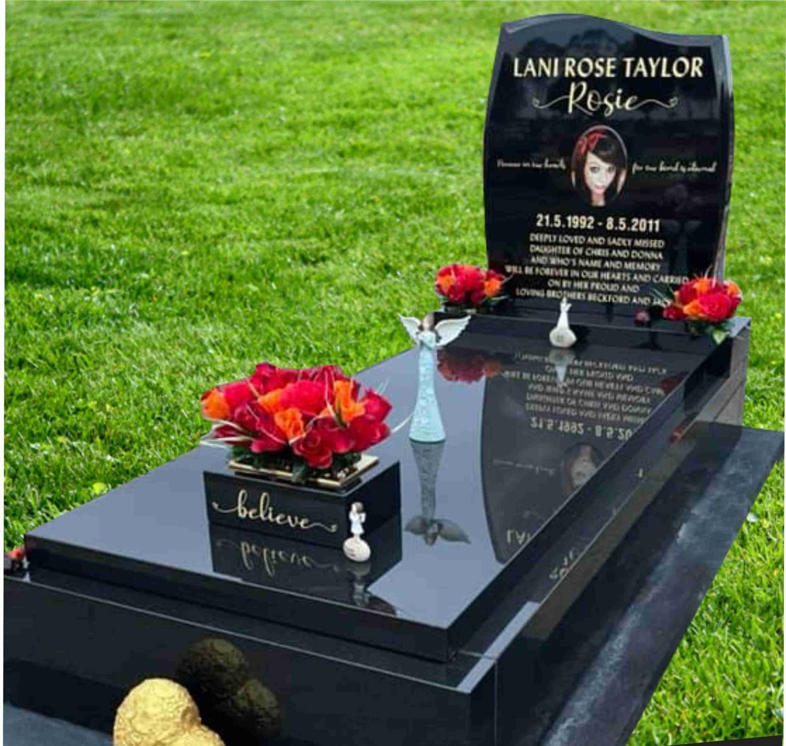 A gravestone with a flower on it in a cemetery.