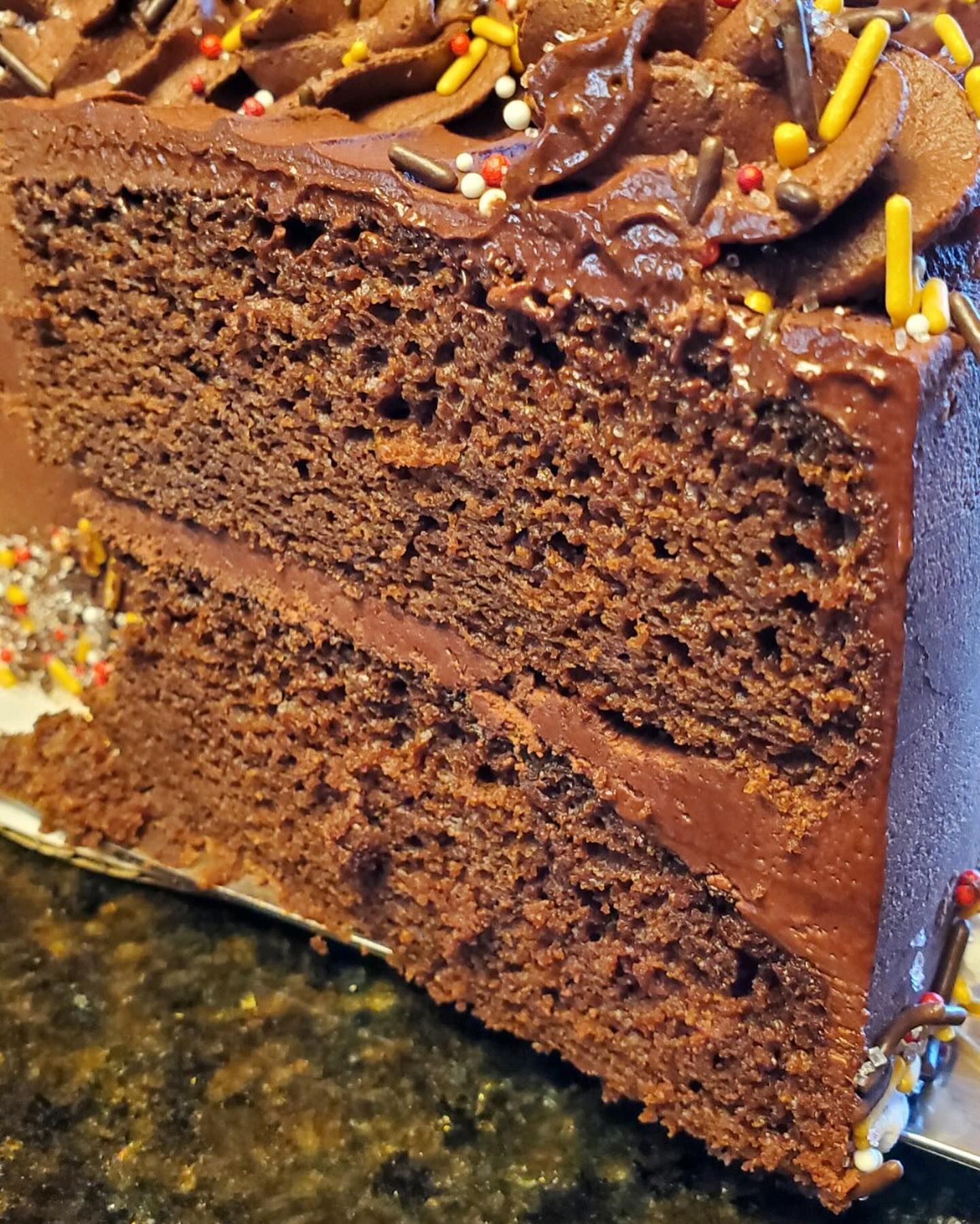 A slice of chocolate cake with frosting and sprinkles