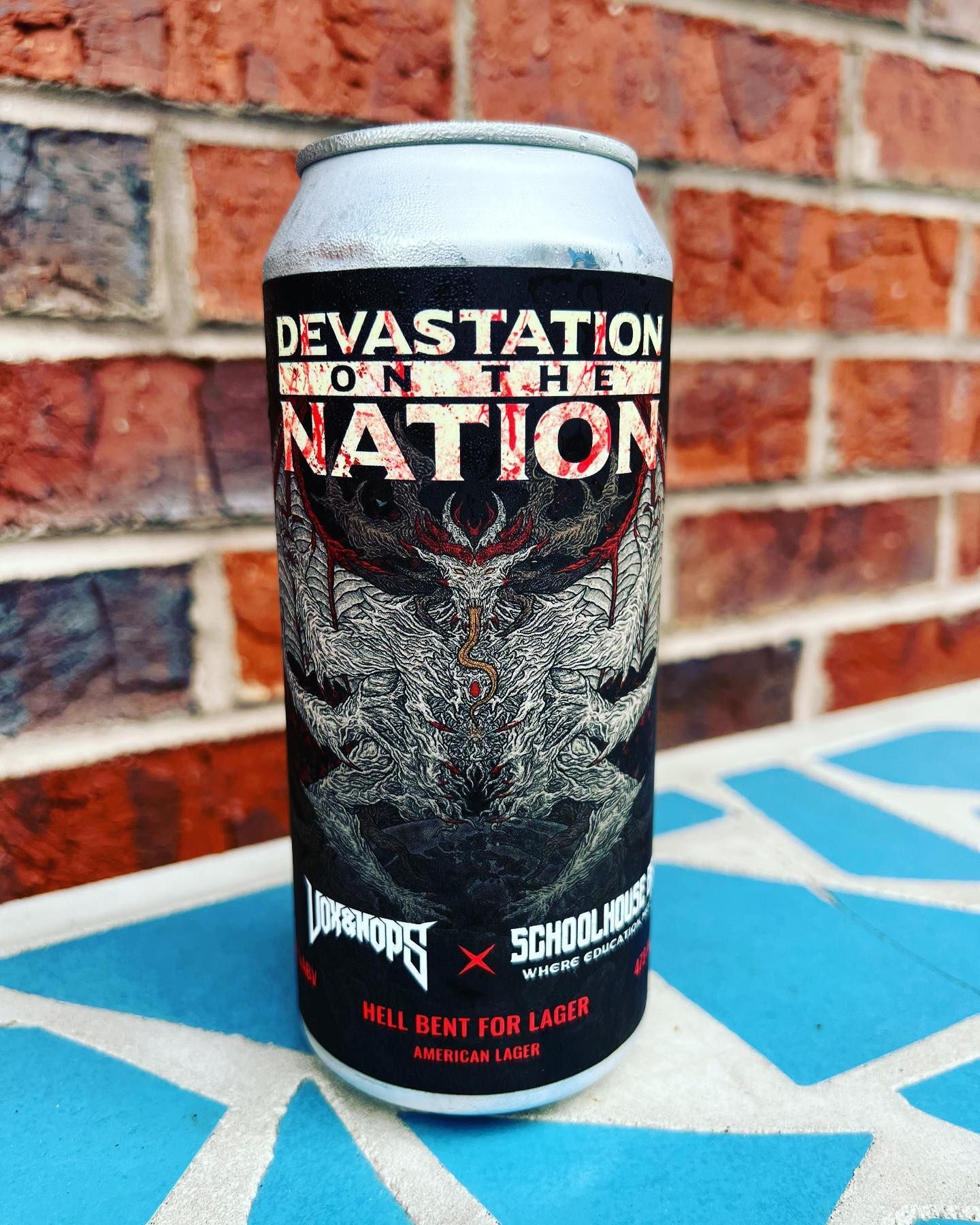 A can of devastation nation beer is sitting on a table in front of a brick wall.