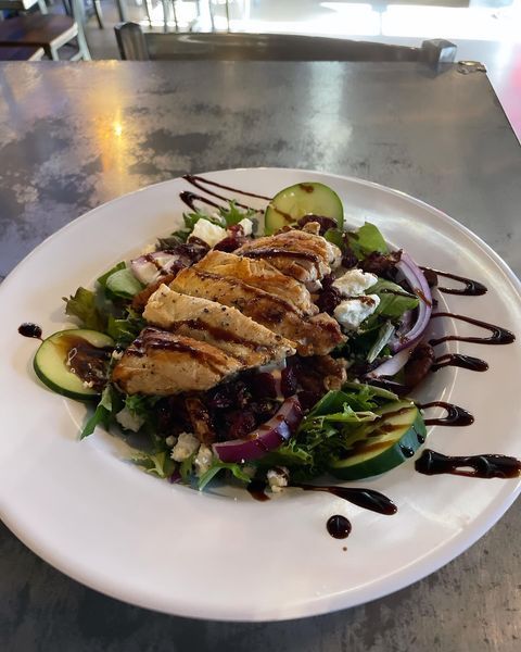 A white plate topped with chicken and vegetables on a table