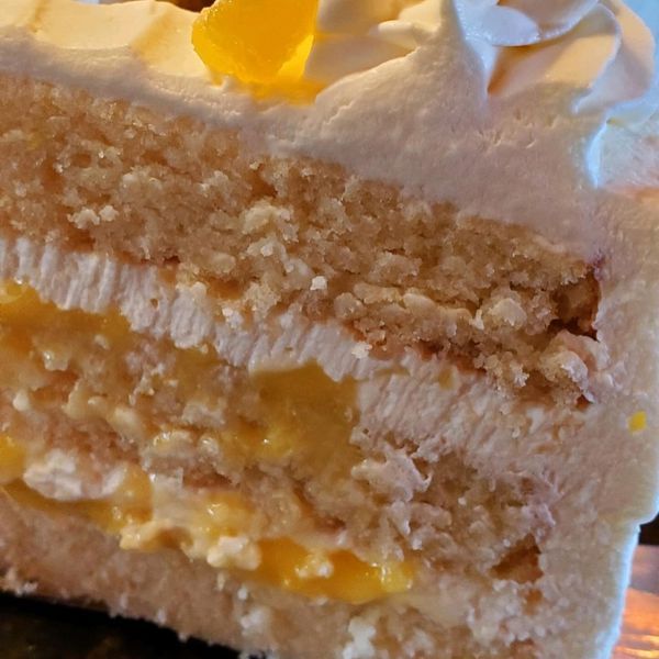 A close up of a slice of cake with whipped cream on top
