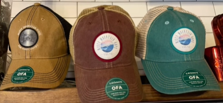 Three baseball caps are sitting on a shelf next to each other.