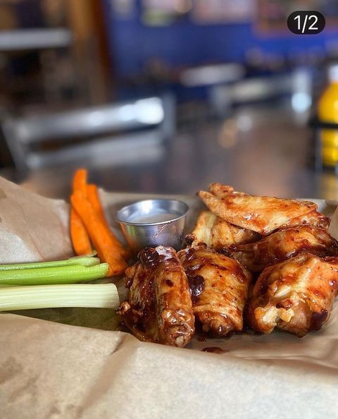 A close up of chicken wings with celery and carrots on a table