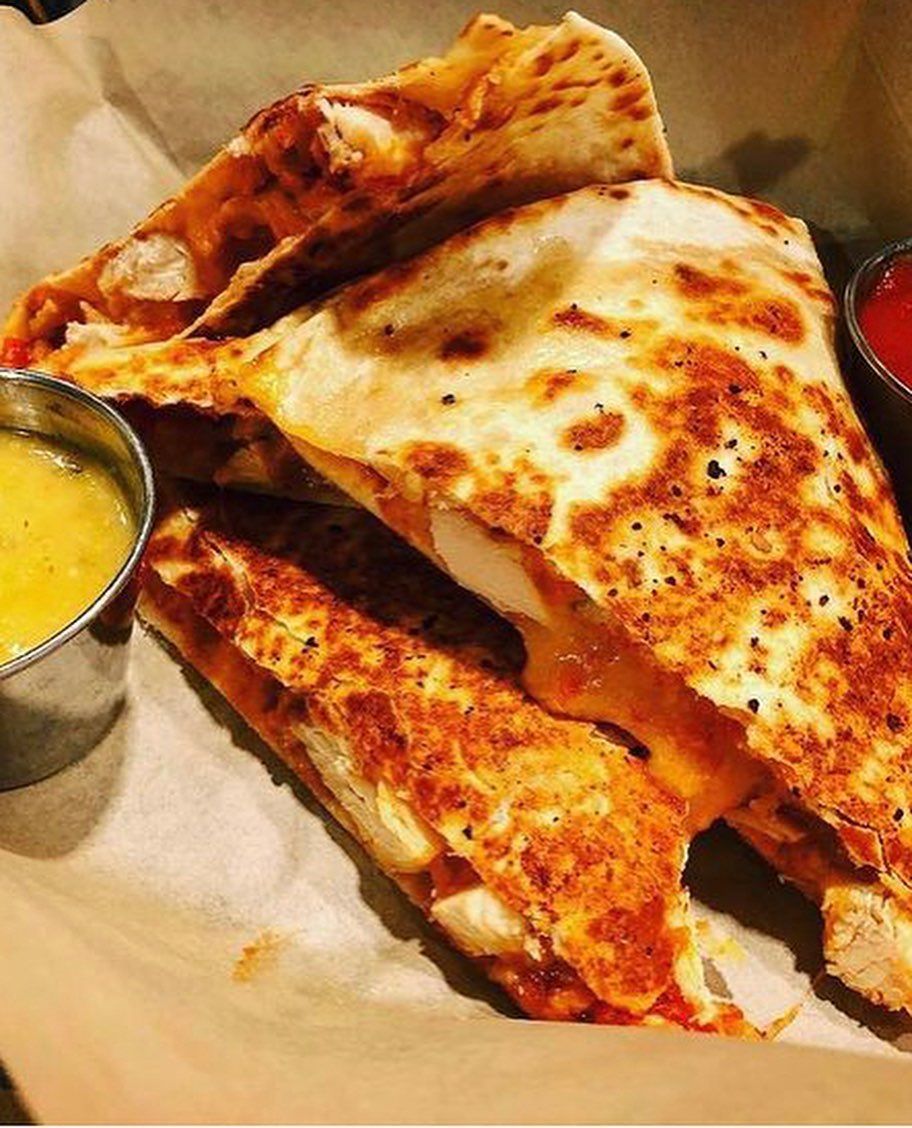 A close up of a quesadilla with a side of dipping sauce
